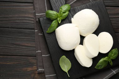 Ahşap masanın üstünde lezzetli mozzarella peyniri ve fesleğen parçaları. Metin için boşluk