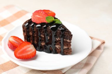 Bir parça çikolatalı kek, beyaz masada çilekli, yakın plan.