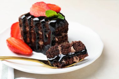 Çilek ve kaşıkla servis edilen bir parça çikolatalı pasta, yakın plan.