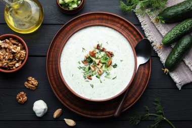 Dereotu ve cevizli lezzetli salatalık çorbası siyah ahşap masada servis edilir.