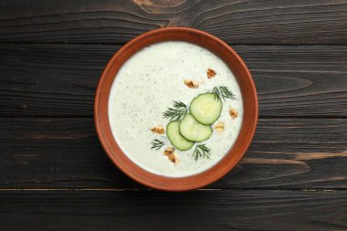 Ahşap masada dereotlu ve cevizli leziz salatalık çorbası.