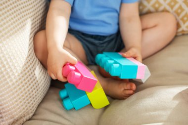 Evdeki kanepede tuğlalarla oynayan sevimli küçük çocuk, yakın plan.