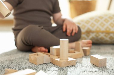 Evdeki ahşap yapı taşlarıyla oynayan sevimli küçük çocuk, yakın plan.