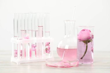 Lüks parfüm yapıyorum. Temel yağlar cam süslemede ve çiçekler beyaz ahşap masada, yakın plan.