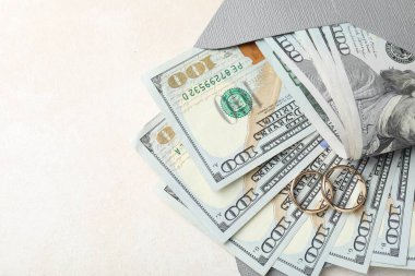 İki altın alyans, bir dolarlık banknotlar ve beyaz masadaki zarf, üst manzara. Metin için boşluk