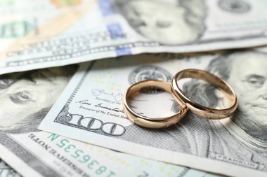 Dolar banknotları üzerinde iki altın alyans, yakın plan.