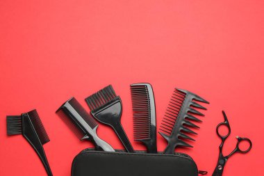 Farklı kuaför aletleri ve kırmızı arka planda çanta, düz yatış. Metin için boşluk
