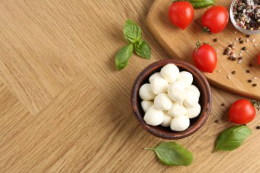 Lezzetli mozzarella topları, domatesler, biberler ve fesleğenler ahşap masada, düz yatak. Metin için boşluk