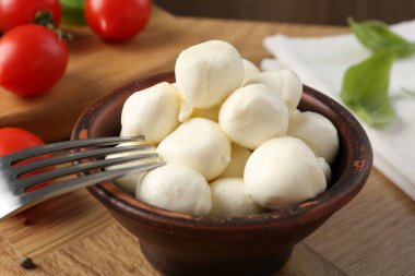 Lezzetli mozarella topları, domatesler ve fesleğenler ahşap masada, yakın plan.
