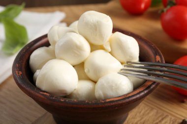 Lezzetli mozarella topları, domatesler ve fesleğenler ahşap masada, yakın plan.