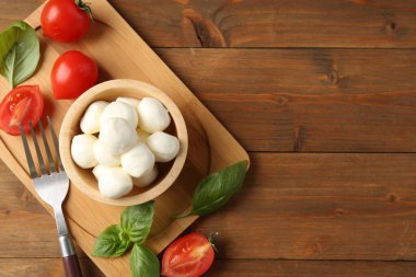Lezzetli mozzarella topları, domates ve fesleğen, ahşap masa, düz yatak. Metin için boşluk