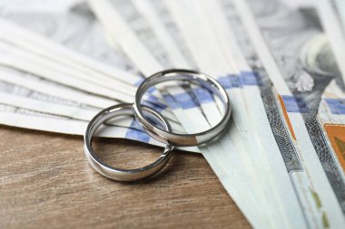 Gümüş alyanslar ve dolar banknotları ahşap masada, yakın plan.