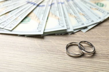 Gümüş alyanslar ve dolar banknotları ahşap masada, yakın plan. Metin için boşluk