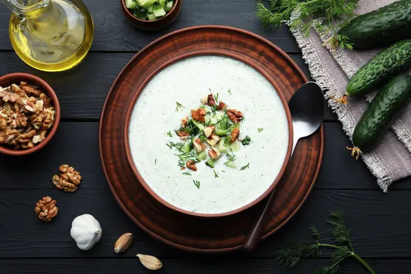 Dereotu ve cevizli lezzetli salatalık çorbası siyah ahşap masada servis edilir.