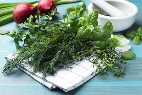 Mavi ahşap masada farklı otlar ve baharatlar, yakın plan.