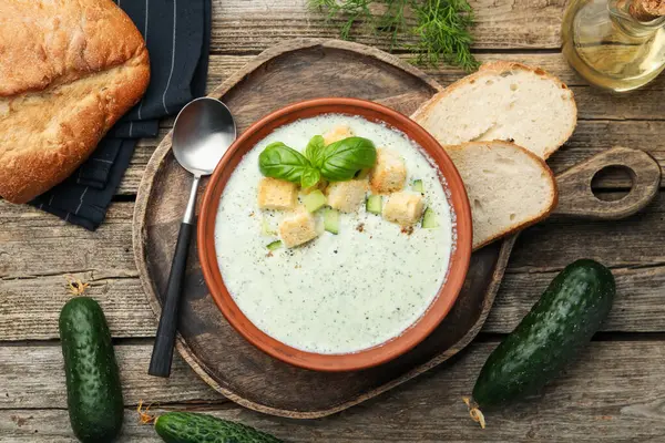 Tahta masada servis edilen kıtır kıtır salatalık çorbası ve fesleğen.