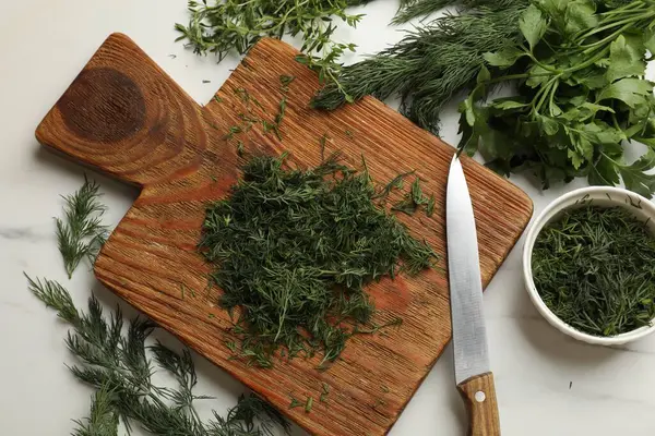 Farklı taze otlar ve beyaz mermer masa üzerinde bıçak, düz.