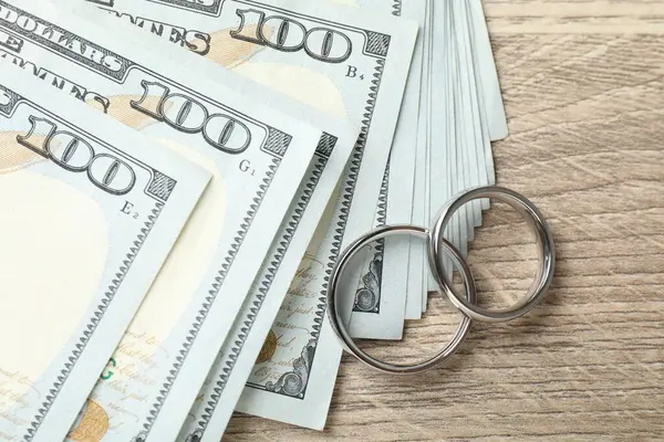 Gümüş alyanslar ve dolar banknotları ahşap masada, düz yatıyordu.