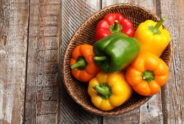 Taze renkli dolmalık biberler hasır sepetin içinde ahşap masanın üstünde, üst tarafta.