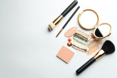 Farklı kozmetik ürünleri, makyaj fırçaları ve beyaz arka planda ayna, düz yatak. Metin için boşluk
