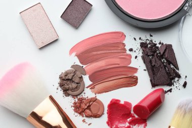 Beyaz arka planda farklı kozmetik ürünler ve makyaj fırçaları, düz yatış