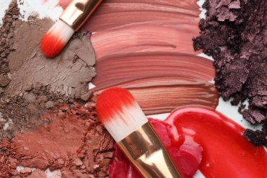 Beyaz arka planda farklı kozmetik ürünler ve makyaj fırçaları, düz yatış