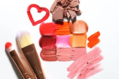 Beyaz arka planda farklı kozmetik ürünler ve makyaj fırçaları, düz yatış