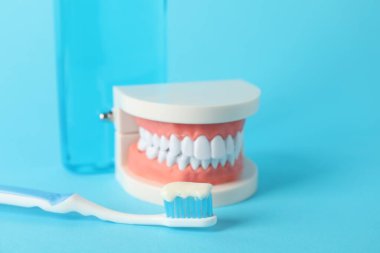 Diş macunu, gargara ve diş fırçası açık mavi arka planda, yakın plan.