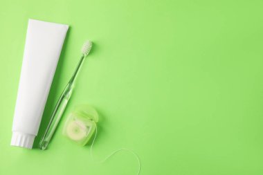 Diş fırçası, diş macunu ve yeşil arka planda diş ipi. Metin için boşluk
