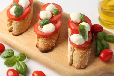 Peynirli, domatesli ve fesleğenli lezzetli sandviçler beyaz masanın üstünde.