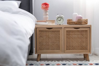Yatağın yanında alarm saati ve dekorasyonu olan komodinin yanında.