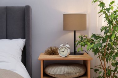 İçinde lamba, çalar saat ve yatağın yanında dekor olan komodin. İç tasarım