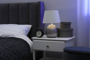 İçinde lamba, çalar saat ve yatağın yanındaki dekorun bulunduğu komodin.