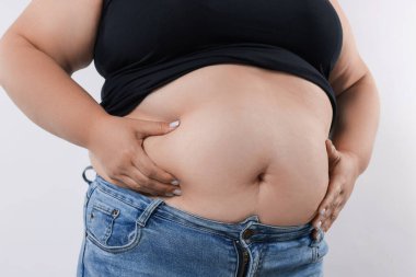 Beyaz arka planda aşırı göbek yağı olan kadın, yakın plan.