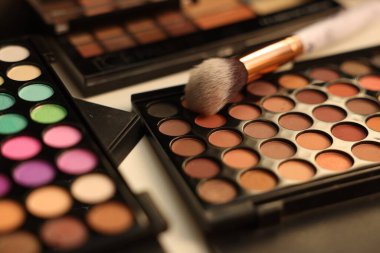 Farklı makyaj ürünleri ve makyaj masasında fırça, yakın çekim.
