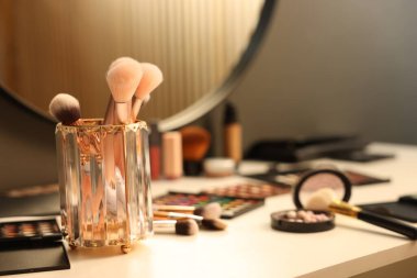 Tuvalet masasında farklı makyaj ürünleri ve fırçalar var.