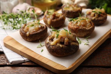 Eritilmiş peynirli lezzetli mantarlar ve ahşap masadaki kekik, yakın plan.