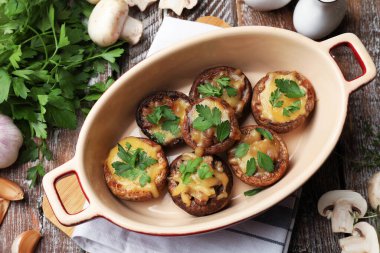 Pişirme kabında lezzetli mantarlar ve renkli ahşap masa üzerinde ürünler.