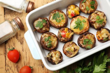 Ahşap masaya konmuş, ahşap tabakta ve malzemelerde lezzetli mantarlar var.