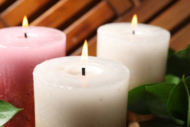 Masada yanan mumlar ve yeşil yapraklar, yakın plan.