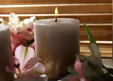 Yanan mumlar ve zambak çiçekleri masada, yakın plan.