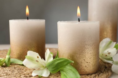 Yanan mumlar ve zambak çiçekleri masada, yakın plan.