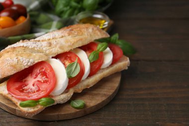 Mozarella peynirli, domatesli ve ahşap masadaki fesleğenli lezzetli sandviç, yakın plan. Metin için boşluk