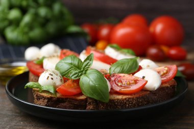 Peynirli, domatesli, fesleğenli ve baharatlı lezzetli sandviçler ahşap masada, yakın plan.