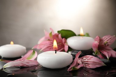 Yakıcı mumlar ve ıslak siyah masada güzel çiçekler, yakın plan. Metin için boşluk