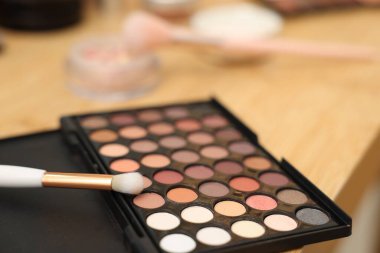 Göz farı paleti ve ahşap masada fırça, yakın plan.