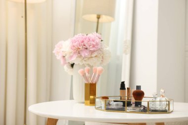 Beyaz masadaki farklı makyaj ürünlerinin olduğu tepsi.