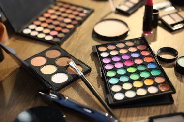 Ahşap masada farklı makyaj ürünleri, yakın plan.