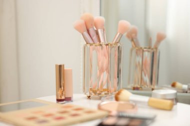 Beyaz masadaki farklı makyaj ürünleri ve fırçalar.