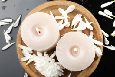 Yanan mumlar ve siyah masada güzel çiçekler, düz uzanmış